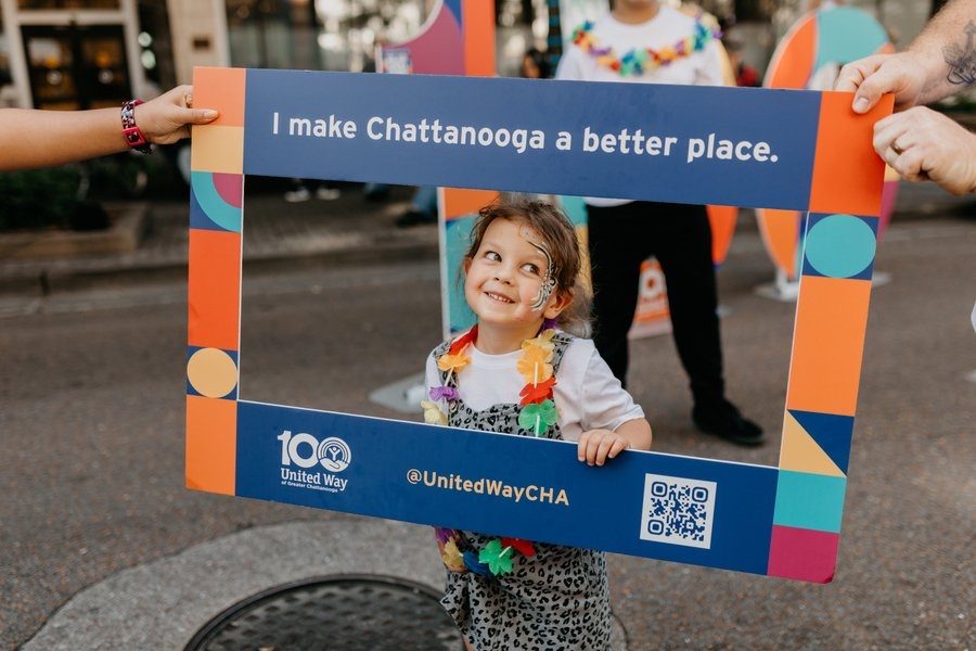 A child holding up a United Way photo frame that reads 'I make Chattanooga a better place'