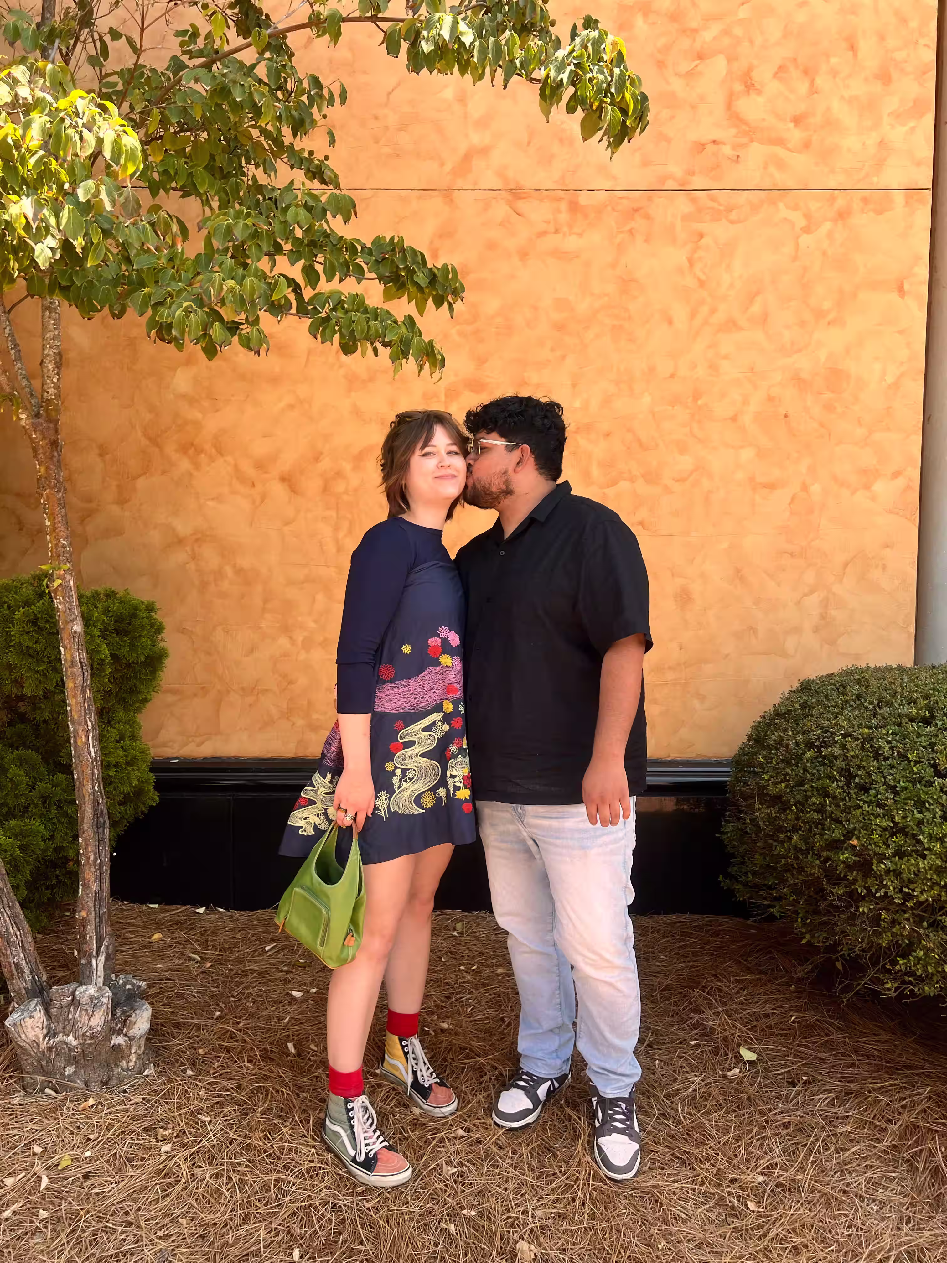 Lizzy and her partner outside a sunlit wall
